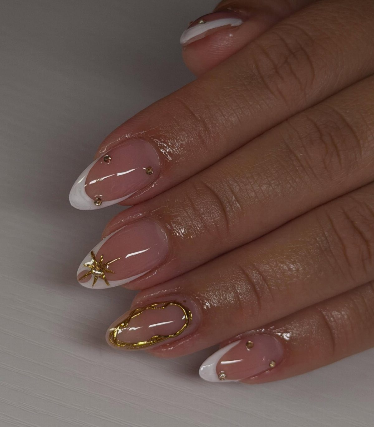 Manicured nails with white French tips and gold star and stud accents.